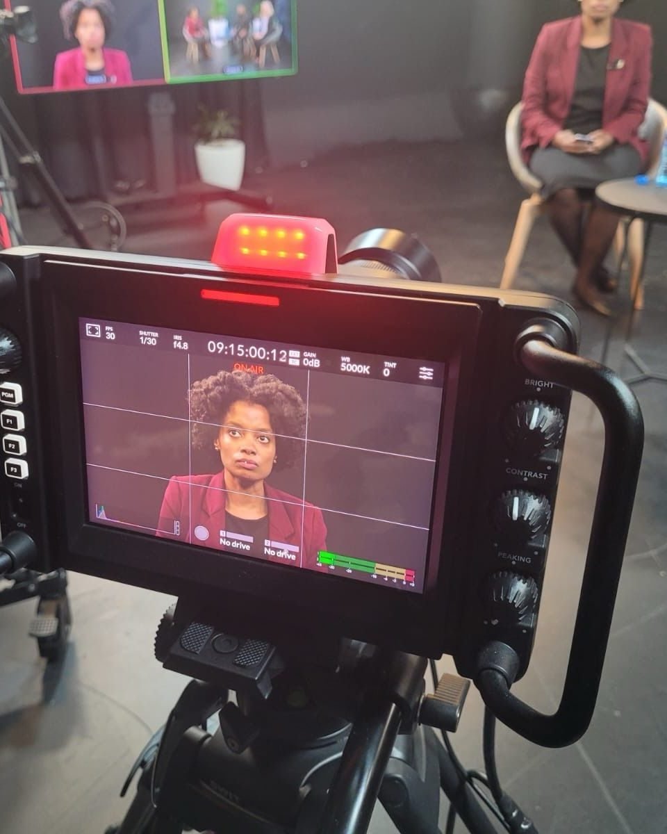 A studio camera monitor showing Maud Nale on air